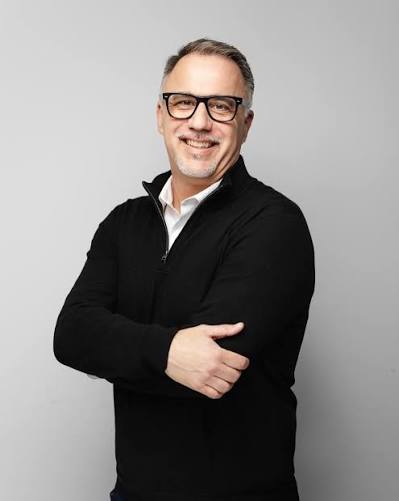 Glenn Issler, mortgage broker, smiling in front of a pale grey wall