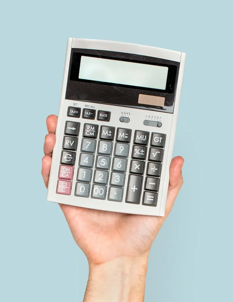 A hand holding an upright calculator against a pale blue background